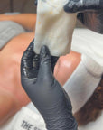 Person wearing black gloves holding a HOP 24k PLLA facial mask with visible brand name Skin Accord.