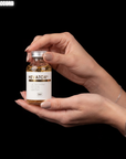 Hand holding a Hevatox Gold Ampoule skincare product against a black background