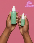 Two hands holding KRX Cica Recovery Serum bottles in 50ml and 15 ml sizes with a pink background and 'Skin Accord'