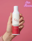 Hand holding a bottle of Krx Aesthetics face wash against a pink background