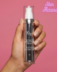 Hand holding KRX Aesthetics Face Lift Intensive Firming Serum bottle with 'Skin Accord' branding on a pink background