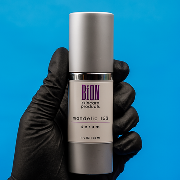 Bion skincare serum bottle held by a gloved hand against a blue background at Skin Accord