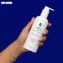 Hand holding a white bottle labeled 'ACFIT V-SANG GEL' against a blue background