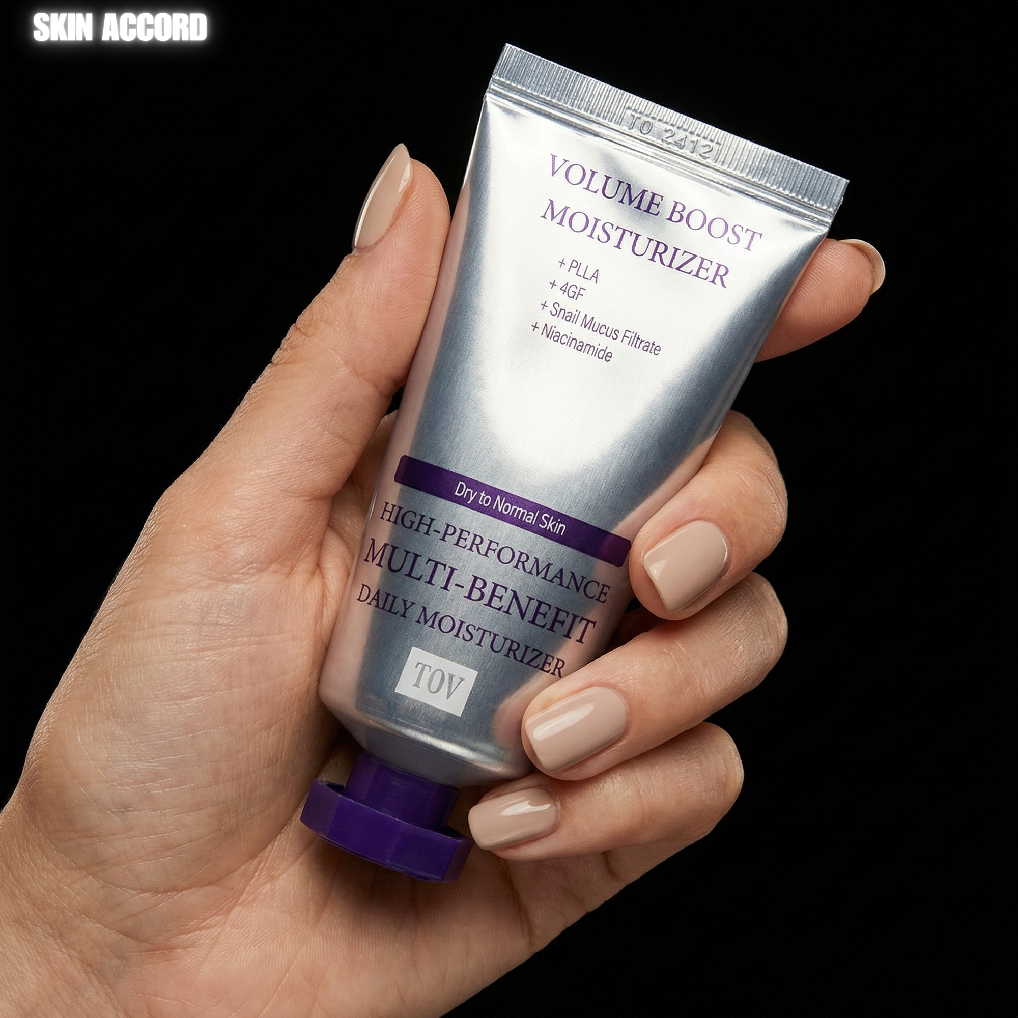 Hand holding a tube of HOUSE OF PLLA HOP+ Volume Boost Moisturizer against a black background