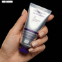Hand holding a tube of HOUSE OF PLLA HOP+ Volume Boost Moisturizer against a black background