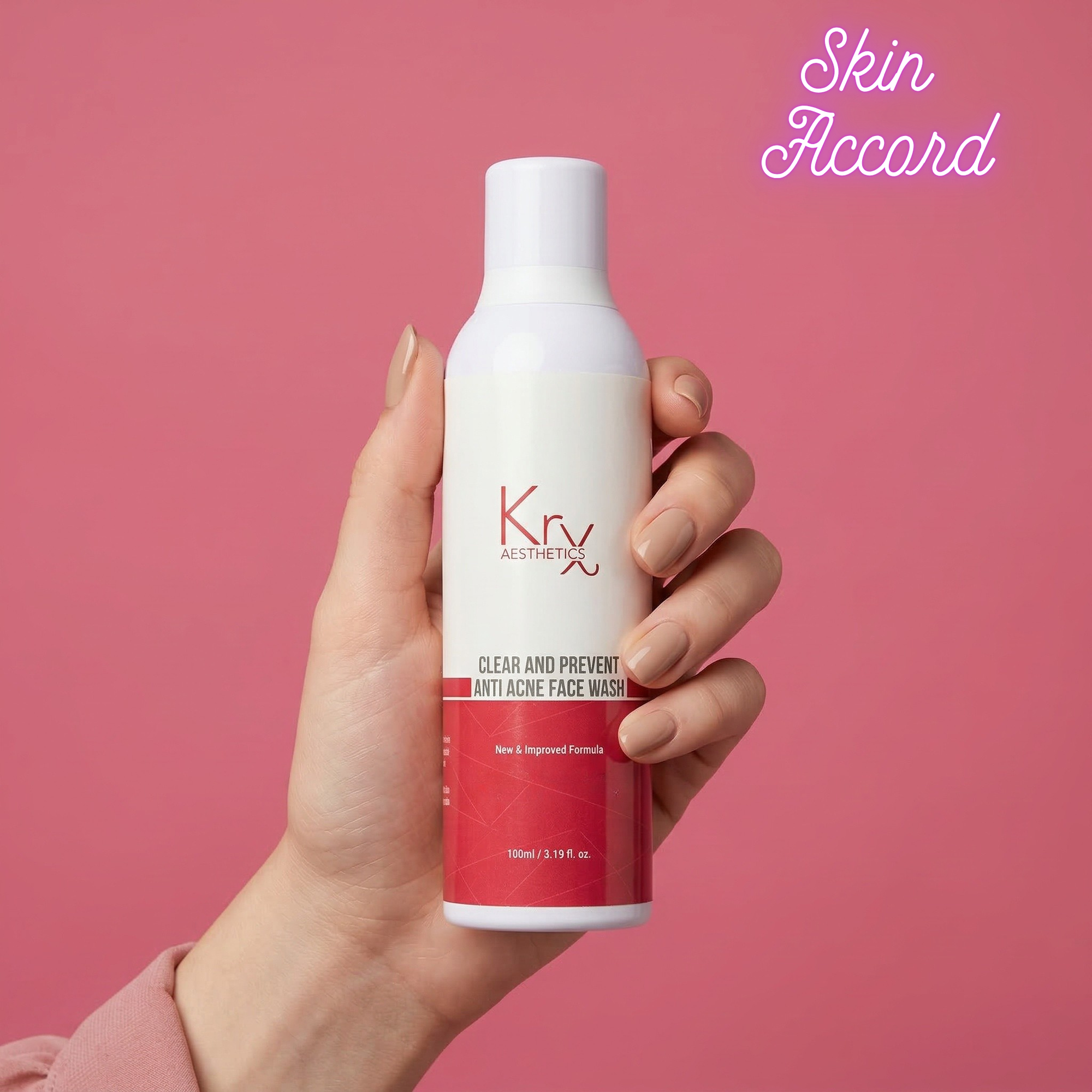 Hand holding a bottle of Krx Aesthetics face wash against a pink background