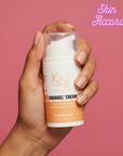 Hand holding a container of Krx Aquagel Cream with a pink background