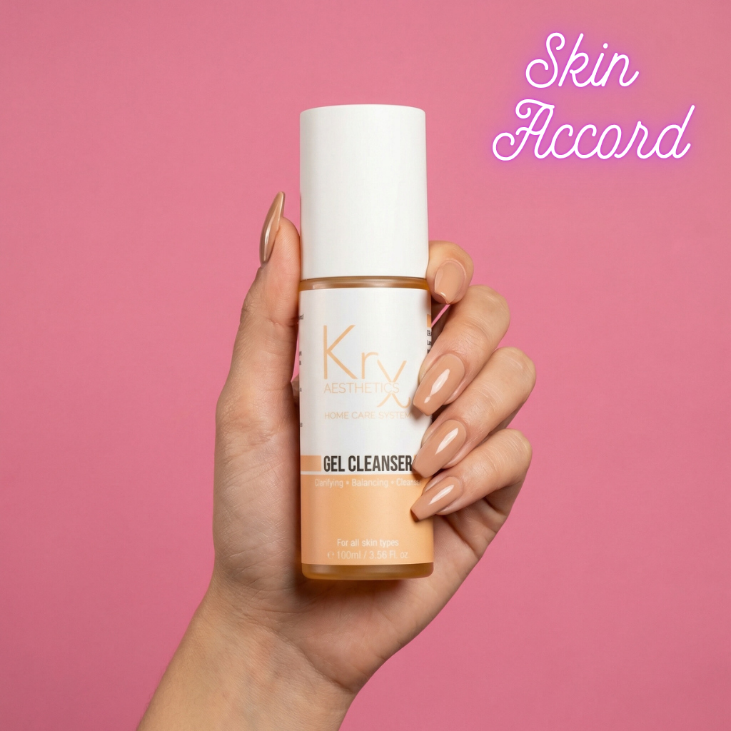 Hand holding a bottle of KRX Aesthetics Glow  gel cleanser against a pink background with 'Skin Accord' text.