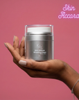 Hand holding a jar of  KRX Aesthetics Mela Defense Cream against a pink background