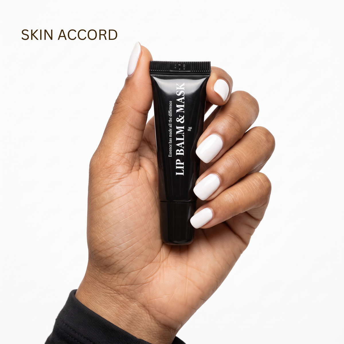 A hand with white manicured nails holds a black squeeze tube of Medi Pair Lip Balm &amp; Mask against a clean white background, with the brand name 'SKIN ACCORD' printed in brown text in the upper left corner.